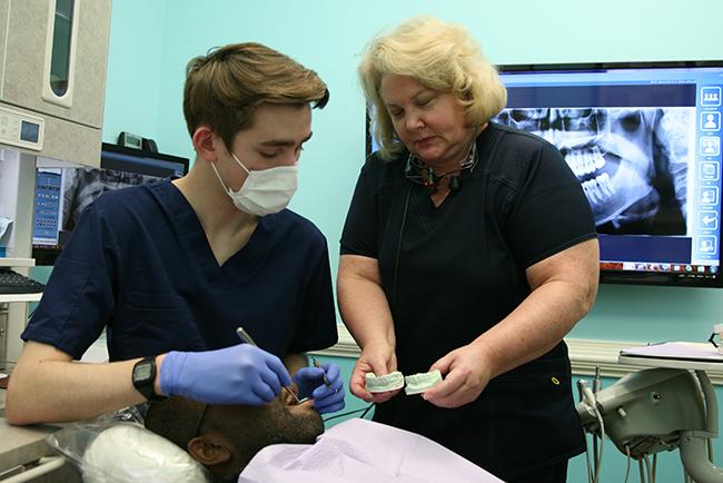 Dentist supervising a student intern with patient in a dentist's chair